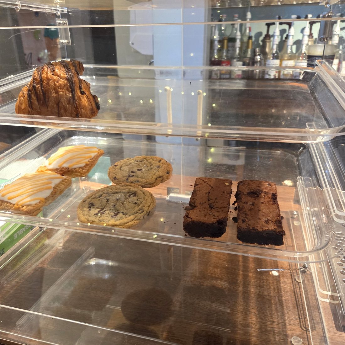 The lower shelf of the case at Icebergs with chocolate chip cookies, two brownies, iced pop tarts and a chocolate croissant.